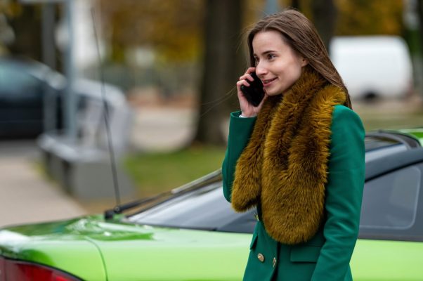 bussines woman using mobile phone, standing near car on street or parking