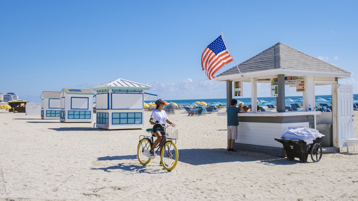 Young women on the beach Miami with a bicycle, colorful Miami beach Florida